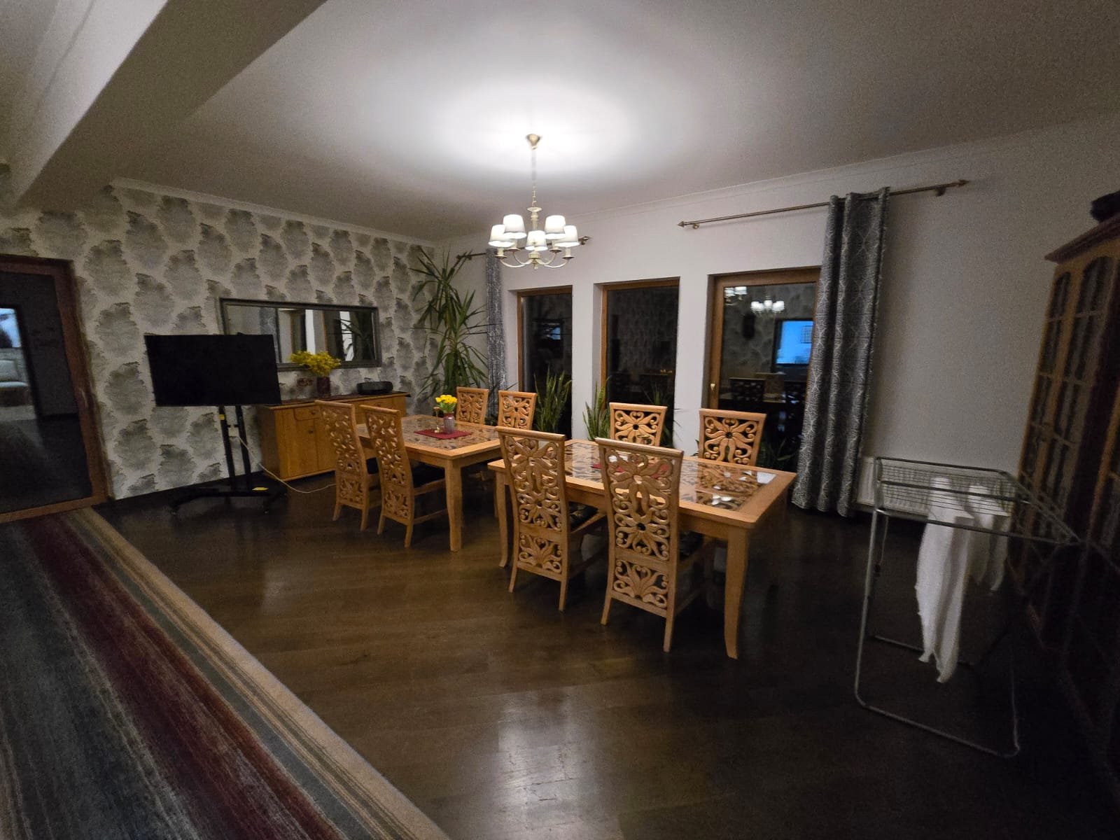 Wspólna jadalnia z drewnianym stołem i ośmioma rzeźbionymi krzesłami